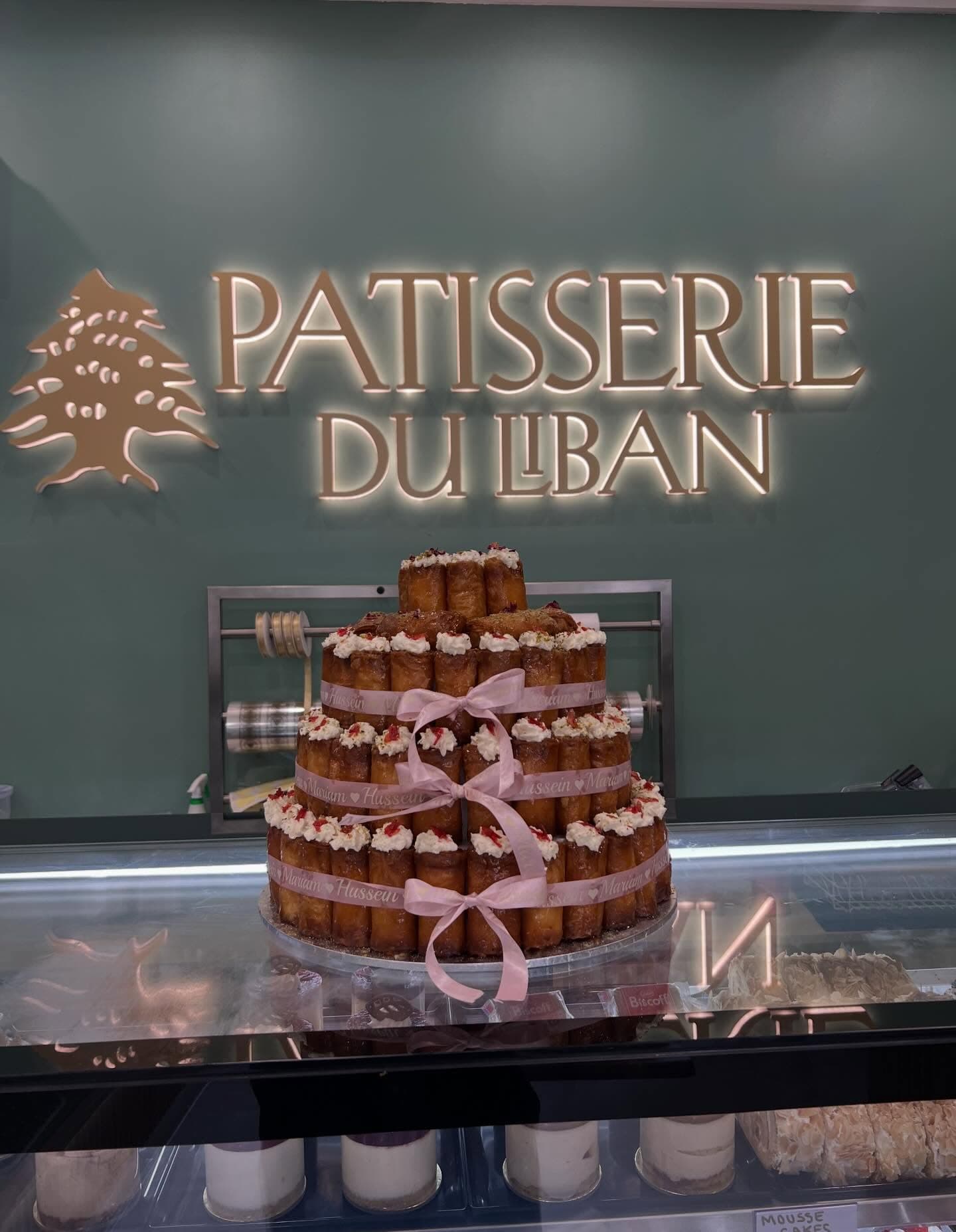 Tiered dessert tower of znoud el sit pastries with pink ribbons.